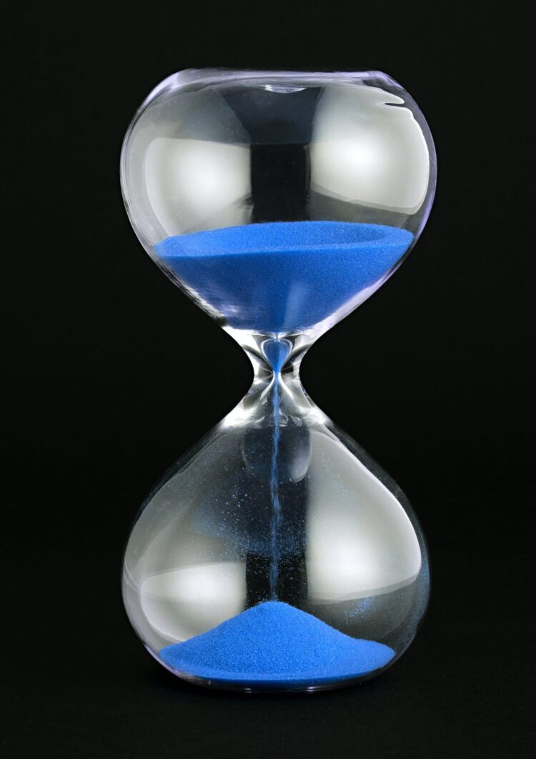 Close-up of a transparent hourglass with blue sand