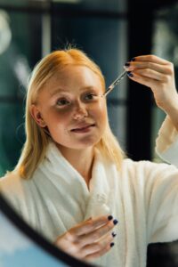 Woman wearing a bathrobe applying serum to her face